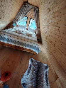 a bedroom with a bed in a log cabin at Carpatina Runcu căsuțe tip A in Runcu +7 photos