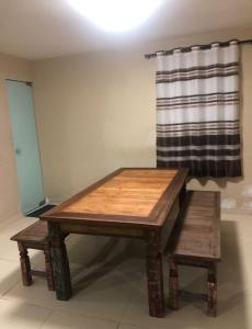 a wooden table and bench in a room with a curtain at Iane Raquel Bezerra Barbosa in Tamandaré