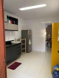 a kitchen with a refrigerator and a white tile floor at Iane Raquel Bezerra Barbosa in Tamandaré