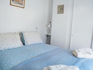 a bedroom with a bed with blue sheets and pillows at Rose Cottage in Low Bradley