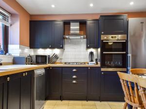 eine Küche mit dunkelblauen Schränken und einem Waschbecken in der Unterkunft Bow Cottage in Bourton on the Water