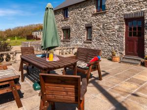 ein Holztisch mit einem grünen Sonnenschirm und Stühlen in der Unterkunft Carn Llidi Cottage in St. Davids + 28 Fotos