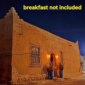 a building with two potted plants in front of it at chez aubazine in Merzouga