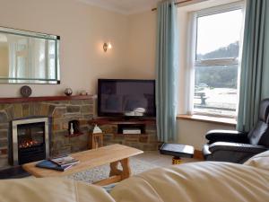 Una sala de estar con chimenea y televisión. en Yorke Villa, en Fishguard