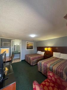 una habitación de hotel con dos camas y un televisor de pantalla plana en Western Capri Motel, en Tulsa