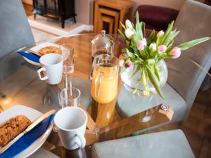 a glass table with a vase of flowers and orange juice at Bosun's Cabin - Uk6719 in Lydstep
