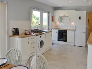 a kitchen with white appliances and a table and chairs at Rotherwood in Portinscale