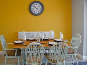 a dining room table with chairs and a clock on the wall at Rotherwood in Portinscale
