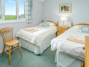 a bedroom with two beds and a chair and windows at Six The Square - Uk48869 in Belford