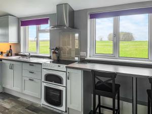 a kitchen with a stove and a sink and two windows at Six The Square - Uk48869 in Belford