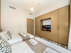 a bedroom with two beds and a tv on the wall at NEW 1BR in DOWNTOWN I 100m Walk to DUBAI MALL I Amazing POOL with Burj View in Dubai