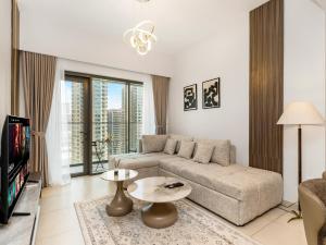 a living room with a couch and a tv at NEW 1BR in DOWNTOWN I 100m Walk to DUBAI MALL I Amazing POOL with Burj View in Dubai