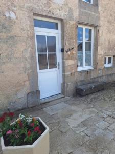 a white door of a building with flowers in front at Chez Riri in Saints-Geosmes