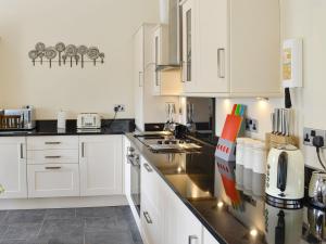 a kitchen with white cabinets and a black counter top at Sgubor Ucha in Trefriw