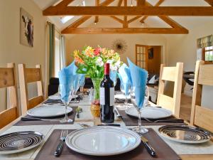 een eettafel met een fles wijn en bloemen bij Llanlliwe Cottage in Henllan Amgoed