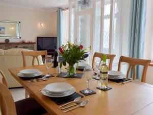 Una mesa de madera con platos y vasos y un jarrón de flores. en Yorke Villa, en Fishguard