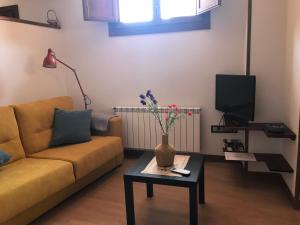 a living room with a couch and a table with flowers at estudio judería in Sigüenza