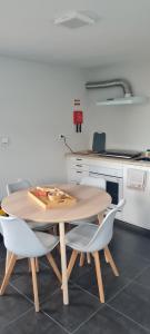 a wooden table and two white chairs in a kitchen at Refúgio das Regadinhas in Santa Cruz