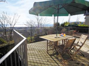 ein Holztisch und Stühle mit einem Sonnenschirm auf einem Deck in der Unterkunft Seacrest Cottage - Hw7746 in Pendine