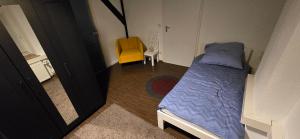 a small bedroom with a bed and a yellow chair at Zentrumsnahe Apartments an der Bucht in Rostock