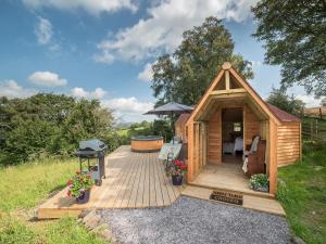 a wooden cabin with a grill and a deck at Dol Y Mynydd The Mountain Meadow - Cottage in Llangernyw