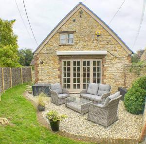 a backyard with wicker chairs and a grill in front of a house at The Barn at The Manor in Cole, Bruton in Cole