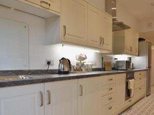 a kitchen with white cabinets and a counter top at 1 School Cottage in Troutbeck Bridge
