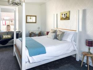 een slaapkamer met een wit bed en een blauwe deken bij Muirston Farmhouse - Uk44977 in Ochiltree