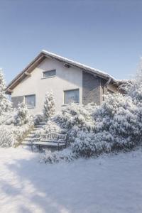 Una casa cubierta de nieve con un banco delante de ella. en U Králíčků, en Vlcice