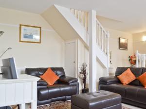 een woonkamer met 2 leren banken en een trap bij Hedderwick House in Pittenweem