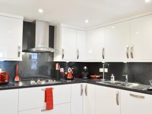 een witte keuken met witte kasten en een spoelbak bij Hedderwick House in Pittenweem