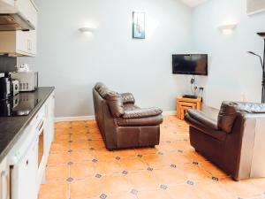 a kitchen with two leather chairs and a television at Gardener's Cottage - Uk6713 in Lydstep