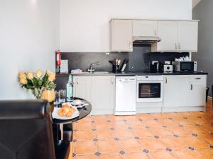 a kitchen with white cabinets and a table with oranges on it at Gardener's Cottage - Uk6713 in Lydstep