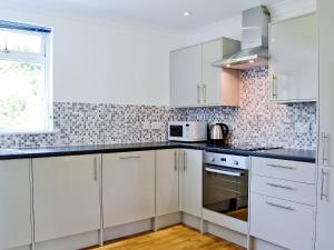 a white kitchen with white cabinets and a window at Torsa - 28790 in Clachan