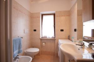 un bagno con lavandino, WC e finestra di Appartamenti Sergio Benedetti a Sappada Altre 27 foto