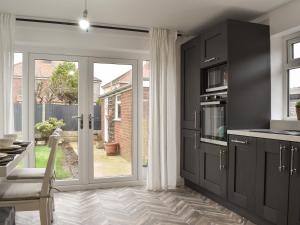 una cocina con armarios negros y una puerta corredera de cristal en Wharfdale Lodge, en Thornton