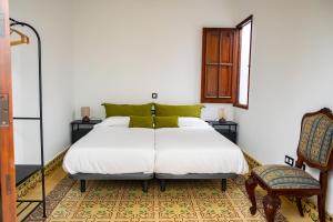 a bedroom with a large white bed and a chair at La Centenaria 1920 in Telde
