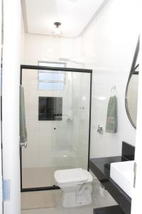ein Badezimmer mit Dusche, Toilette und Waschbecken in der Unterkunft Estudio Novo com ar condicionado e garagem in São Lourenço