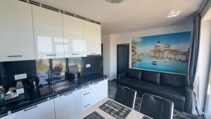 cocina con armarios blancos, fregadero y sofá en LUXE 1 Venezia Suite, en Obzor