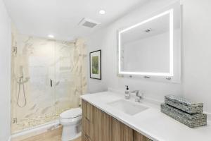 a bathroom with a toilet and a sink and a shower at Elegant Three-Bedroom Oceanfront Apartment with Designer Finishes in South Palm Beach