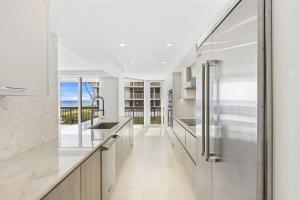 a kitchen with white counters and stainless steel appliances at Elegant Three-Bedroom Oceanfront Apartment with Designer Finishes in South Palm Beach