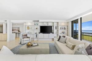 a living room with a couch and a television at Elegant Three-Bedroom Oceanfront Apartment with Designer Finishes in South Palm Beach