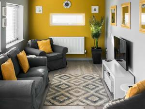 a living room with two couches and a tv at Maes Y Mor in Criccieth