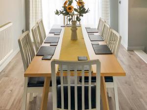 a long wooden table with chairs and a vase of flowers at Maes Y Mor in Criccieth