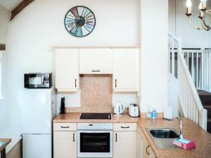 a kitchen with white cabinets and a clock on the wall at Flemish Cottage - Uk6720 in Lydstep