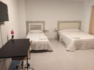 une chambre avec deux lits, un bureau et un miroir dans l'établissement Pensión Alicante Playa, à Alicante 9 autres photos