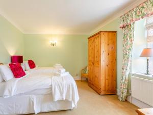 SculthorpeにあるManor Farm House - Uk45276の白いベッドと木製キャビネット付きのベッドルーム1室が備わります。 +7枚の写真