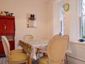 a dining room with a table and chairs and a clock at 1 School Cottage in Troutbeck Bridge