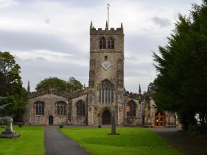 een oud gebouw met een toren met een klok erop bij Church Walk Cottage in Kendal +3 foto's