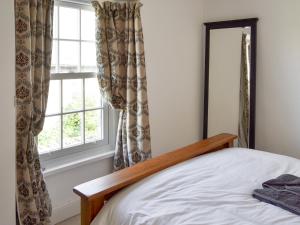 a bedroom with a bed and a window at Woodburn Cottage in Soutergate +7 photos